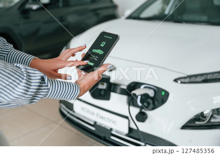 Conception of green energy. Smartphone with charging process data. Close up view of woman 127485356