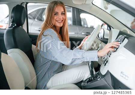 Driving the automobile. Beautiful woman is indoors with the modern car 127485365