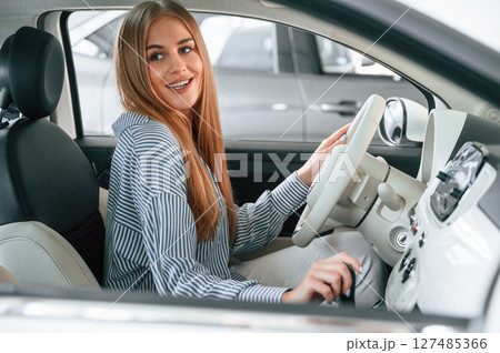 Driving the automobile. Beautiful woman is indoors with the modern car 127485366