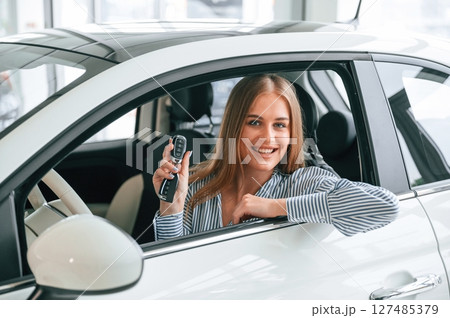 New owner of the car. With keys in hands. Beautiful woman is indoors 127485379