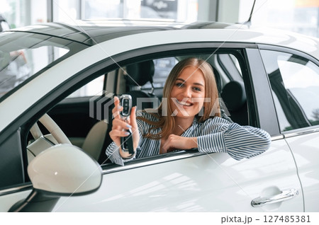 New owner of the car. With keys in hands. Beautiful woman is indoors 127485381