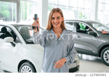 New owner of the car. With keys in hands. Beautiful woman is indoors New owner of the car. With keys in hands. Beautiful woman is indoors 127485401