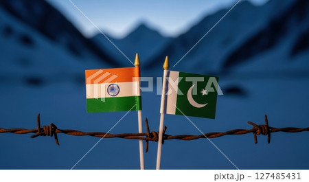 Miniature flags of india and pakistan on barbed wire with mountains, symbolizing border conflict Miniature flags of india and pakistan on barbed wire with mountains, symbolizing border conflict 127485431