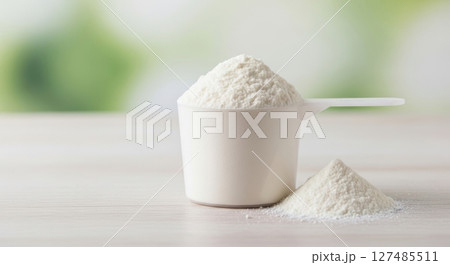 White protein powder in a measuring scoop with a small pile on a light surface White protein powder in a measuring scoop with a small pile on a light surface 127485511