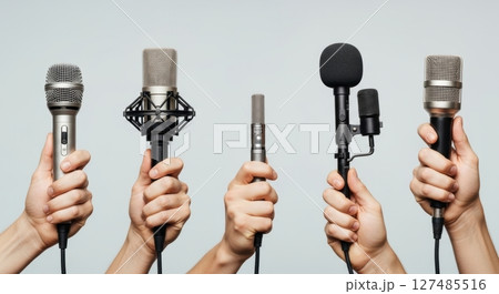 Hands holding a variety of microphones for professional audio and media production 127485516
