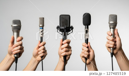 Hands holding various professional microphones for communication, media, and interview concepts 127485519