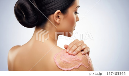 Woman applying pink exfoliating scrub to her shoulder for beauty and skin care 127485563