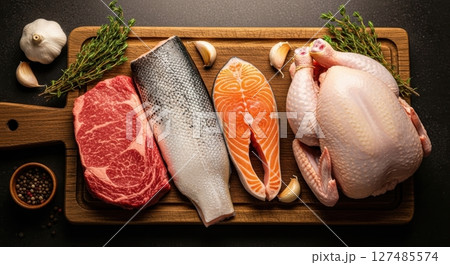 Raw beef steak, whole fish, salmon, and chicken on a wooden board with herbs and spices. Raw beef steak, whole fish, salmon, and chicken on a wooden board with herbs and spices. 127485574