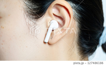 《AI画像》Bluetoothイヤホンを付けた女性のクローズアップ 127486186