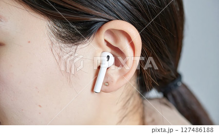 《AI画像》Bluetoothイヤホンを付けた女性のクローズアップ 127486188