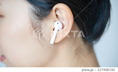 《AI画像》Bluetoothイヤホンを付けた女性のクローズアップ 127486192