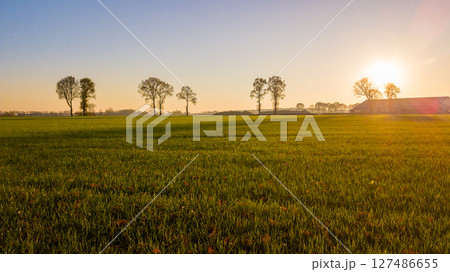 Aerial view on a dramatic and colorful sunrise or sunset sky over a grassy green farmfield shot from Aerial view on a dramatic and colorful sunrise or sunset sky over a grassy green farmfield shot from 127486655