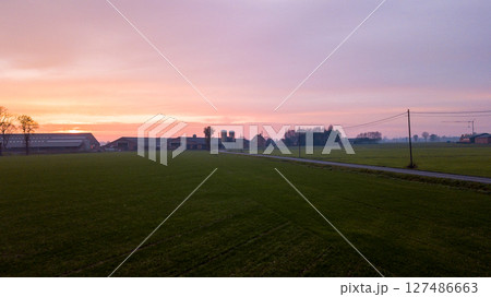 Aerial view on a dramatic and colorful sunrise or sunset sky over a grassy green farmfield shot from Aerial view on a dramatic and colorful sunrise or sunset sky over a grassy green farmfield shot from 127486663