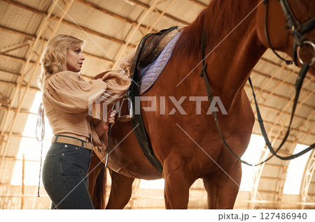 Taking care of animal. Beautiful young woman is with horse indoors Taking care of animal. Beautiful young woman is with horse indoors 127486940