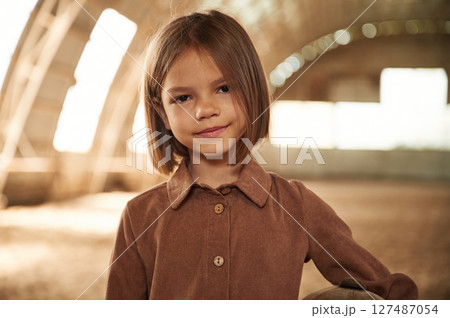 Little girl in jockey clothes is standing indoors 127487054