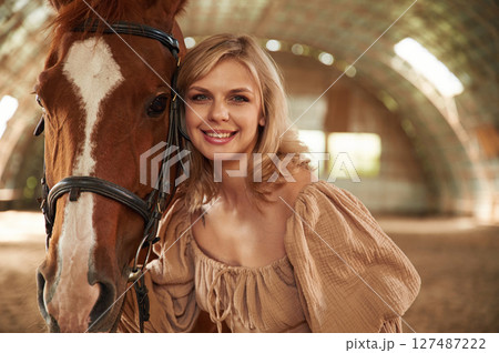 Portrait of beautiful young woman that is with horse indoors 127487222