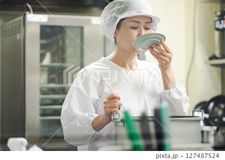 厨房でスープの味見をする調理開発の女性 127487524