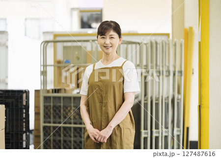 お店のバックヤードで働くエプロン姿のミドル女性 お店のバックヤードで働くエプロン姿のミドル女性 127487616