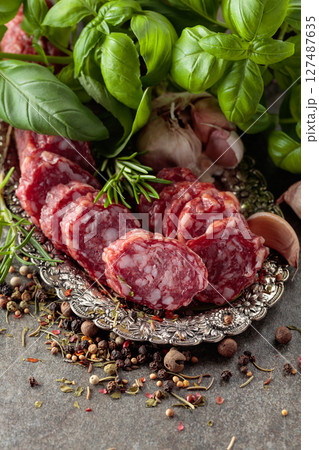 Sliced smoked sausage on a small silver tray. 127487635