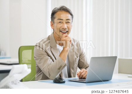 オフィスでデスクワークをする60代のシニア男性 オフィスでデスクワークをする60代のシニア男性 127487645