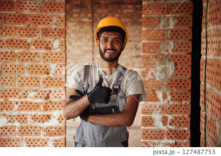Indoors against brick wall. Handsome Indian man is on the construction site 127487753