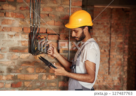 Digital tablet in hands. Handsome Indian man is on the construction site 127487763