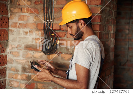 Digital tablet in hands. Handsome Indian man is on the construction site Digital tablet in hands. Handsome Indian man is on the construction site 127487765