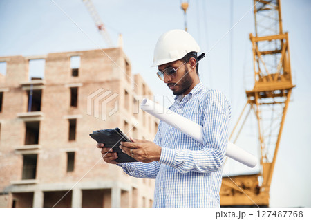 Wireless device in hands, digital tablet. Handsome Indian man is on the construction site 127487768
