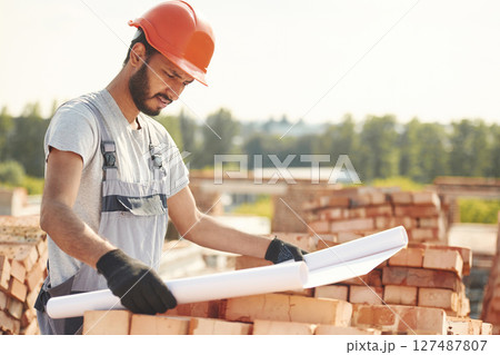 Reading the plan that is in the hands. Handsome Indian man is on the construction site 127487807