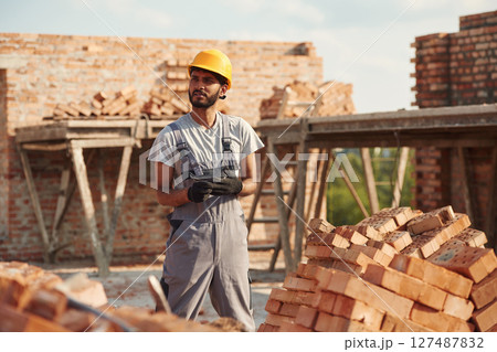 Wearing the gloves. Handsome Indian man is on the construction site Wearing the gloves. Handsome Indian man is on the construction site 127487832
