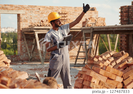 Digital tablet in hands. Handsome Indian man is on the construction site Digital tablet in hands. Handsome Indian man is on the construction site 127487833