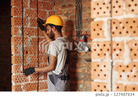 Placing the electricity wires. Handsome Indian man is on the construction site Placing the electricity wires. Handsome Indian man is on the construction site 127487834