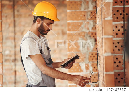 Placing the electricity wires. Handsome Indian man is on the construction site Placing the electricity wires. Handsome Indian man is on the construction site 127487837