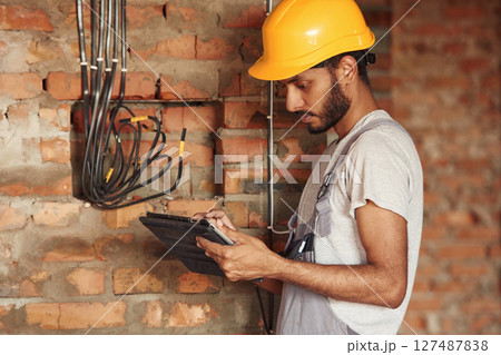 Digital tablet in hands. Handsome Indian man is on the construction site 127487838