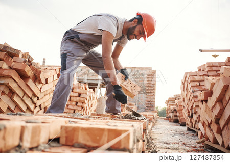Side view, working and placing the bricks. Handsome Indian man is on the construction site 127487854
