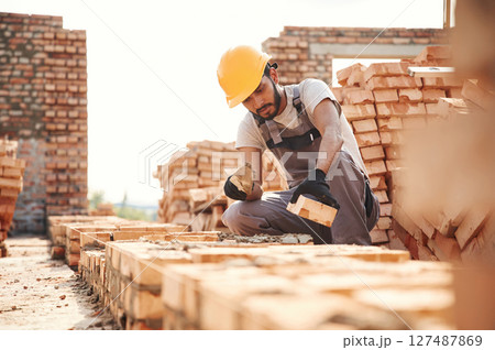 On the top of the building with bricks. Handsome Indian man is on the construction site On the top of the building with bricks. Handsome Indian man is on the construction site 127487869