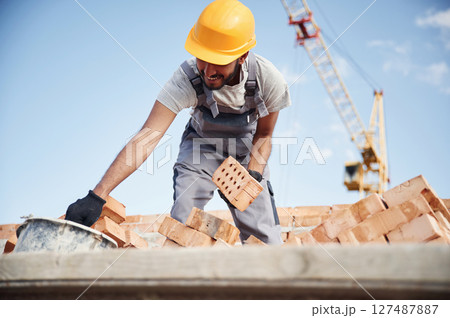 Blue sky and crane is behind. Handsome Indian man is on the construction site 127487887