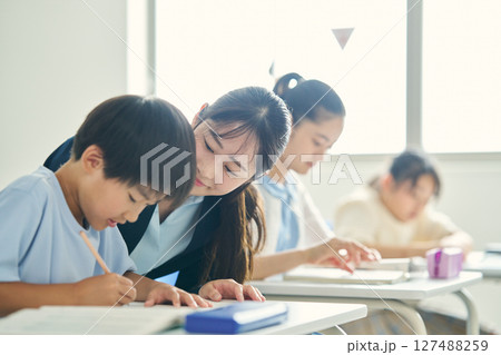 学習塾で子供に指導する講師 127488259