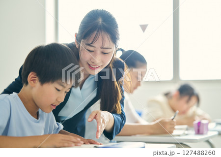 学習塾で子供に指導する講師 127488260