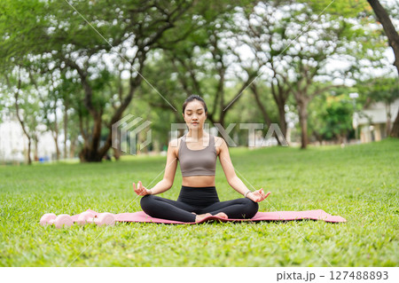 Yoga practice in nature. Young woman meditating peacefully on a yoga mat outdoors. Yoga practice in nature. Young woman meditating peacefully on a yoga mat outdoors. 127488893