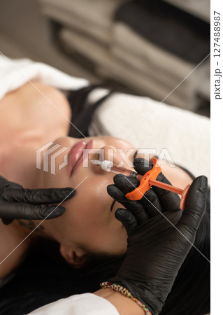 Syringe near woman's chin, beauty injections with fillers for chin shape correction. Syringe near woman's chin, beauty injections with fillers for chin shape correction. 127488987