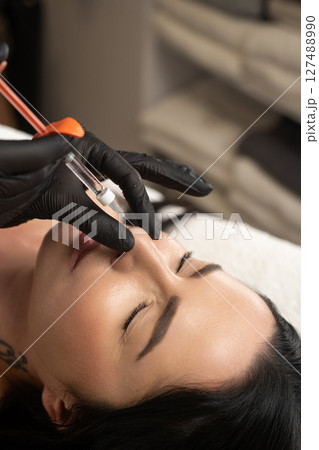 Syringe near a woman's nose, beauty injections with fillers to correct the shape of the nose. Syringe near a woman's nose, beauty injections with fillers to correct the shape of the nose. 127488990