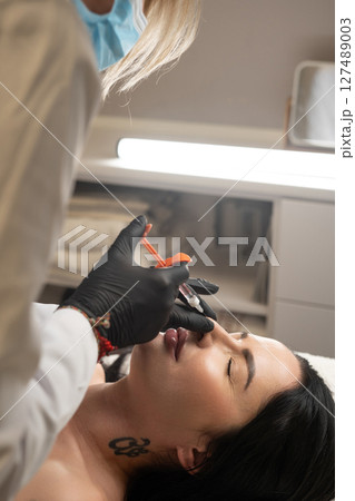Syringe near a woman's nose, beauty injections with fillers to correct the shape of the nose. Syringe near a woman's nose, beauty injections with fillers to correct the shape of the nose. 127489003