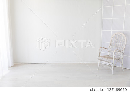 white vintage armchair in the interior of a room with a window 127489650