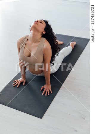 Fitness Woman Brunette Doing Gymnastics Yoga Asana in White Hall 127489721