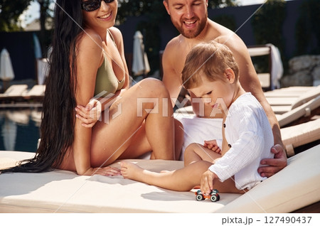 Cheerful people are sitting. Happy family of father, mother and son are in the pool 127490437