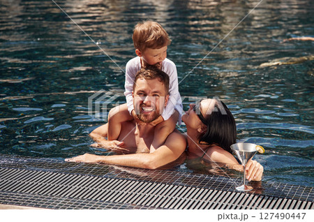 In the water. Happy family of father, mother and son are in the pool In the water. Happy family of father, mother and son are in the pool 127490447