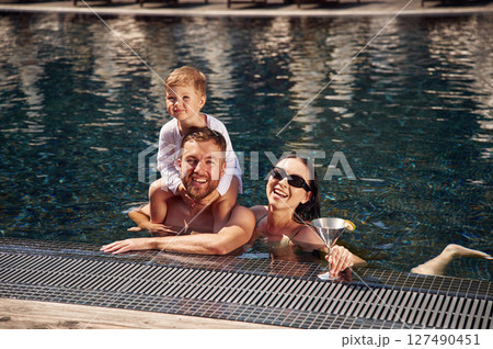 Front view. Happy family of father, mother and son are in the pool Front view. Happy family of father, mother and son are in the pool 127490451