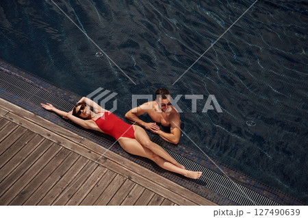 Woman is lying down. Man is in the pool 127490639