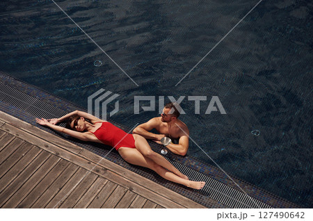 Woman is lying down. Man is in the pool Woman is lying down. Man is in the pool 127490642